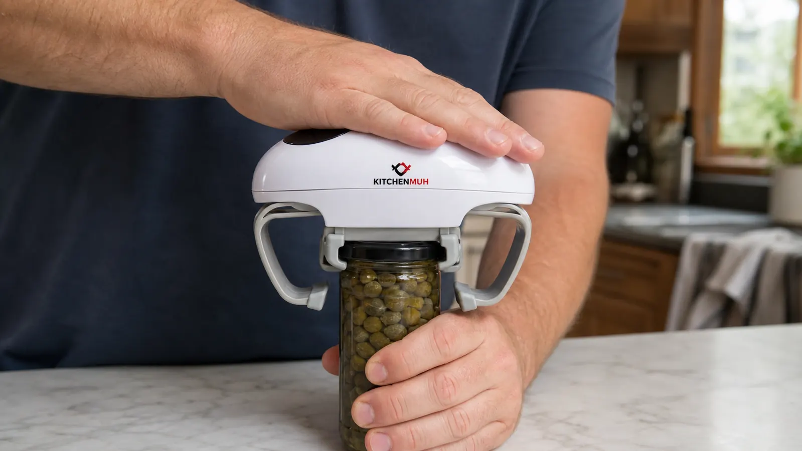 A hand pressing the single button on an electric jar opener clamped over a small squat jar with a metal lid